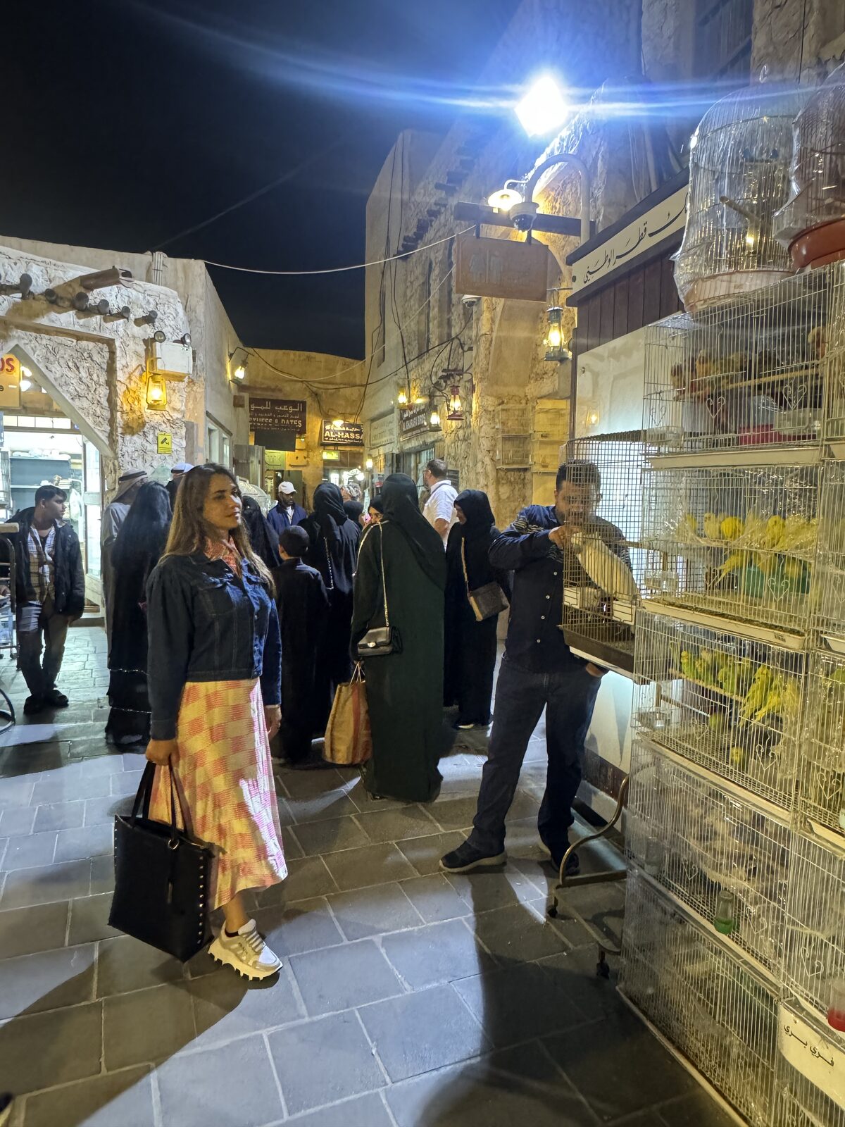 Movimento noturno no mercado de pássaros do Souq Waqif, no Catar, com gaiolas cheias de pássaros