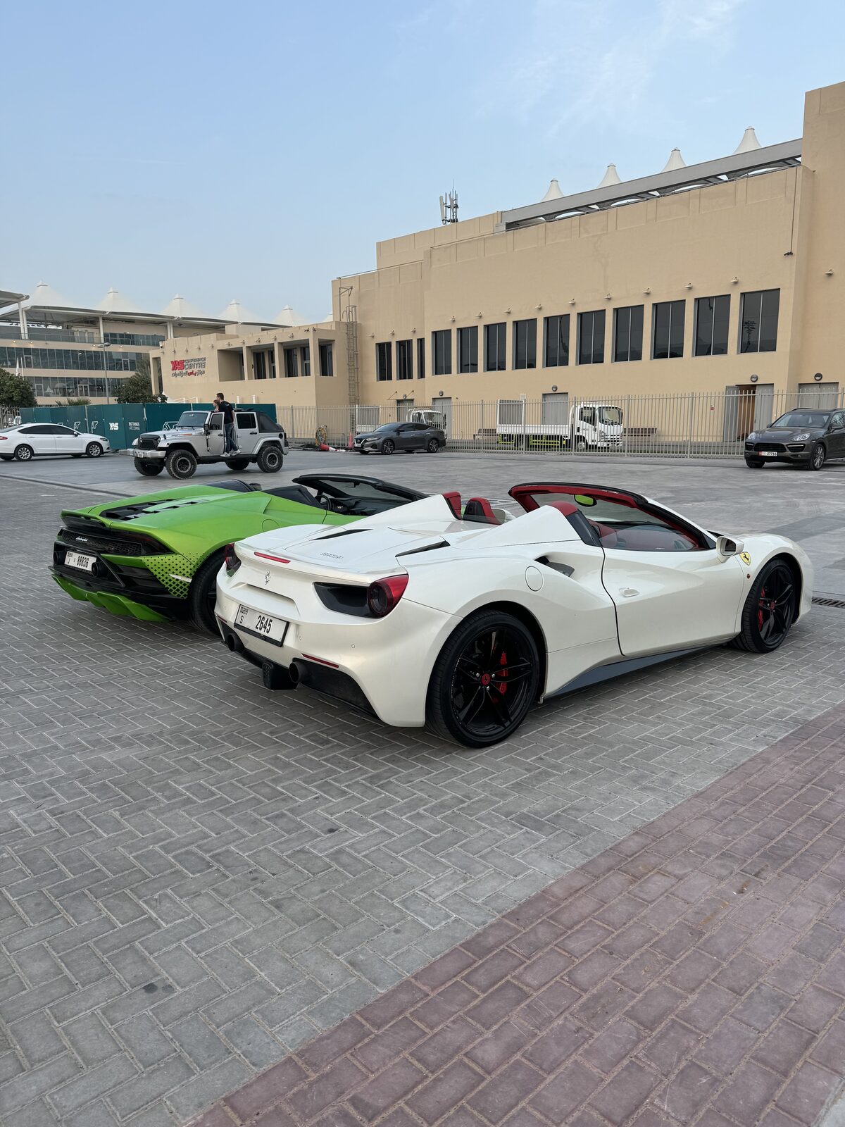 Lamborghini verde e Ferrari branca estacionadas lado a lado em Yas Marina, Abu Dhabi